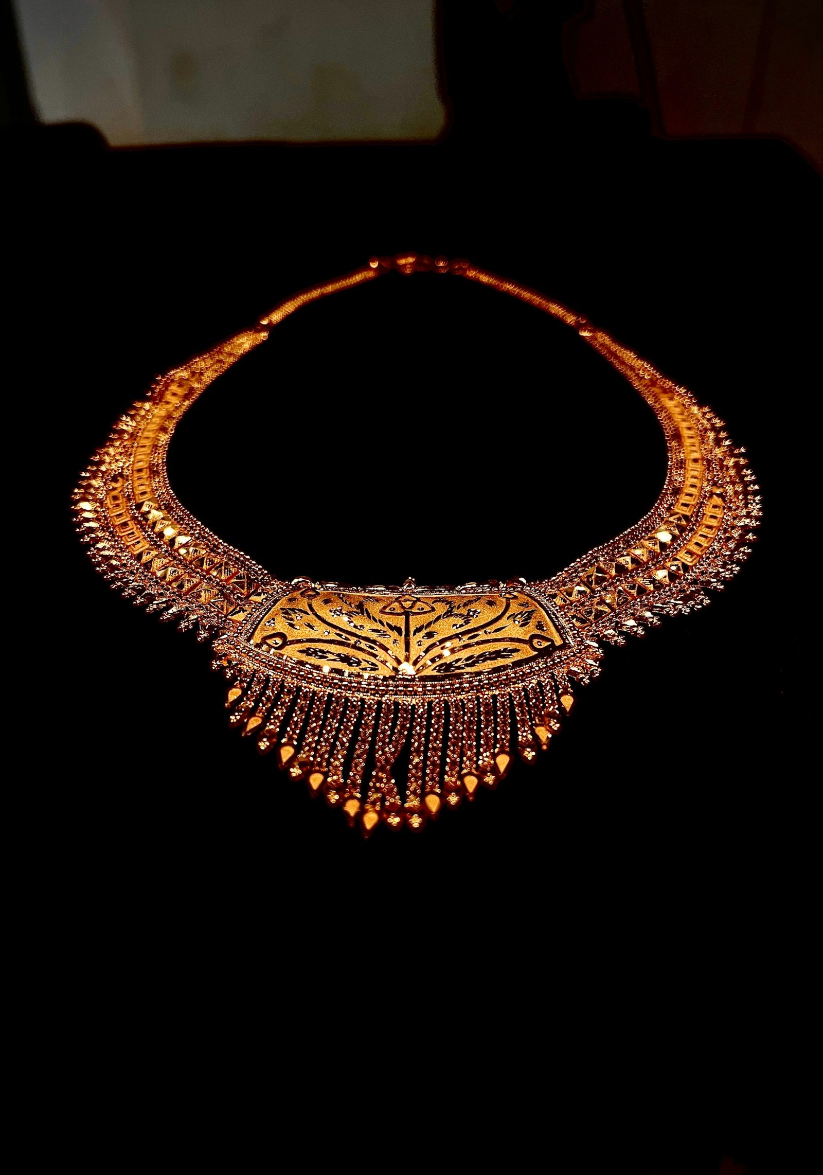 Ornate gold necklace against a dark background